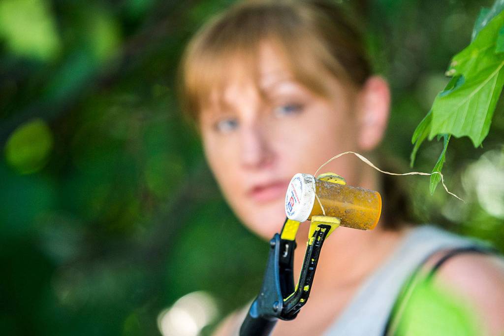 Reagan Mead, who organized a cleanup of central Port Angeles, holds up a pill bottle that she found while cleaning near Lincoln Street on Sunday. (Jesse Major/Peninsula Daily News)