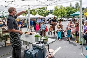 Steve Mullensky/for Peninsula Daily News Arron Stark, executive chef for Jefferson Healthcare in Port Townsend, holds up the peel from a cucumber while giving pointers for cooking healthy foods to kids and adults at the Jefferson County Farmers market on Wednesday. Stark demonstrated the making of a healthy dip for a crudite using fresh peas and cottage cheese as part of World Wide Breast Feeding Week with the emphasis on breast milk as the very first healthy food kids get in life. The program was sponsored by Jefferson Healthcare and Jefferson County Public Health. The demos will repeat on Saturday at the Uptown Farmers Market.