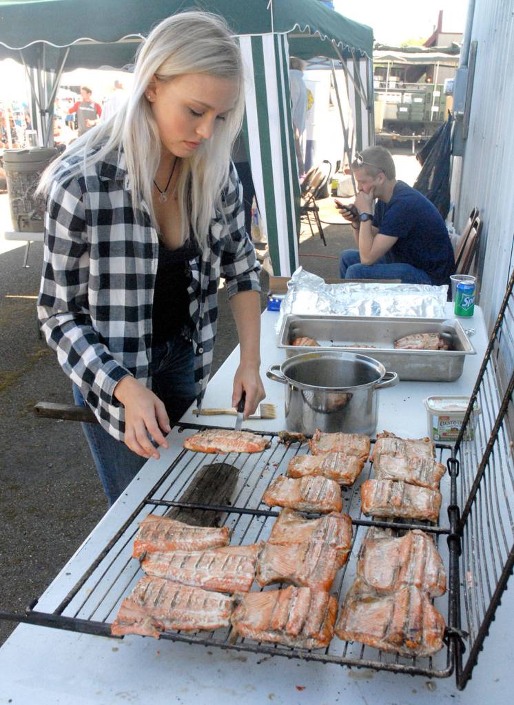 Lauren Hartley prepares salmon planks during a salmon bake hosted by the Crescent Bay Lions Club at the Joyce Daze Wild Blackberry Festival. (Keith Thorpe/Peninsula Daily News)