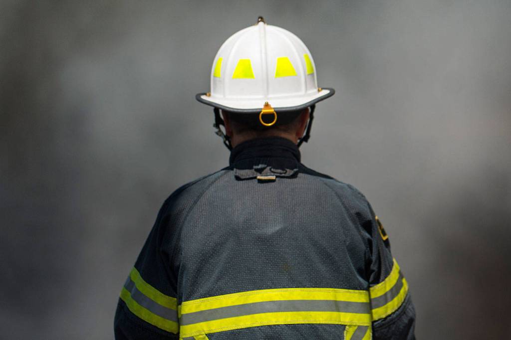Clallam County Fire District No. 2 Assistant Fire Chief Mike DeRousie faces a wall of smoke as firefighters put water on an RV fire on the 2300 block of East Fifth Avenue in Port Angeles on Sunday. (Jesse Major/Peninsula Daily News)