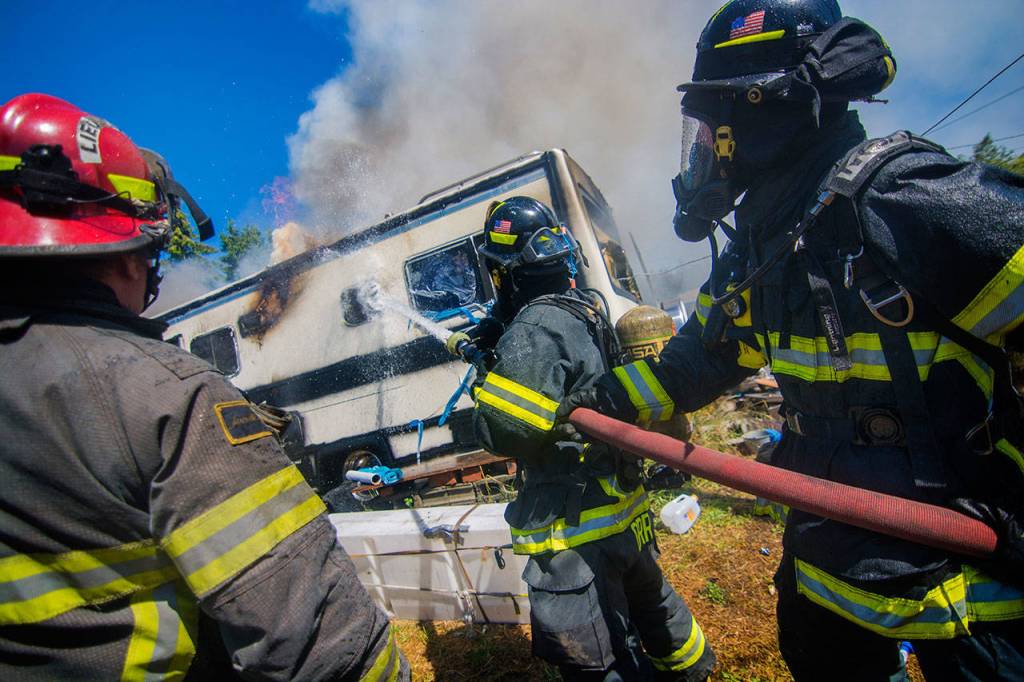 Firefighters put water on an RV fire on the 2300 block of East Fifth Avenue in Port Angeles on Sunday. (Jesse Major/Peninsula Daily News)