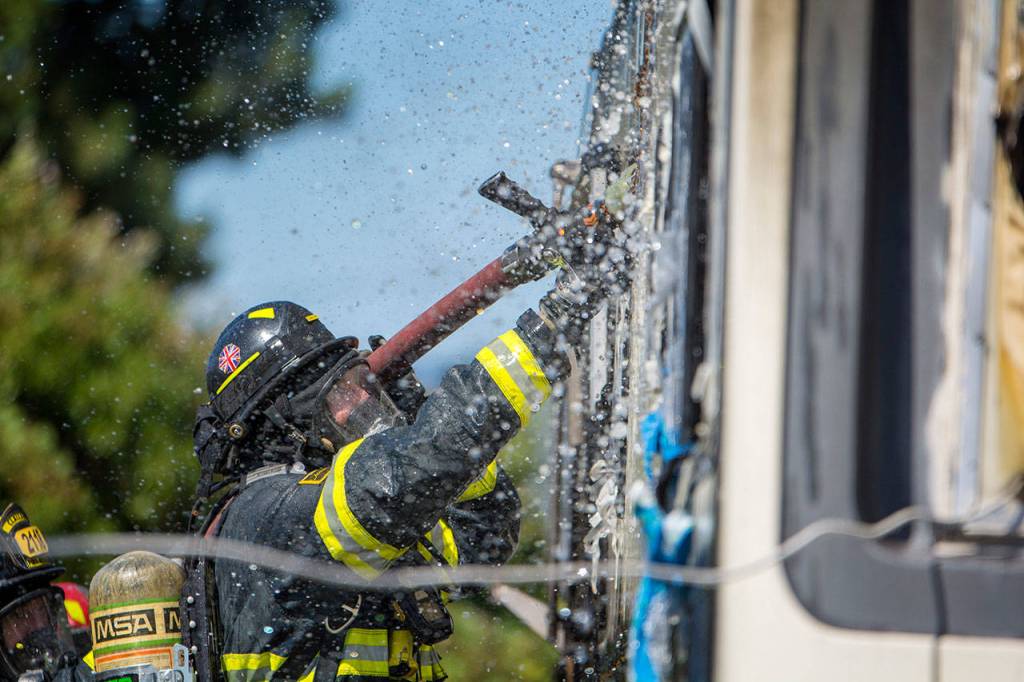 A Firefighter puts water on an RV fire on the 2300 block of East Fifth Avenue in Port Angeles on Sunday. (Jesse Major/Peninsula Daily News)