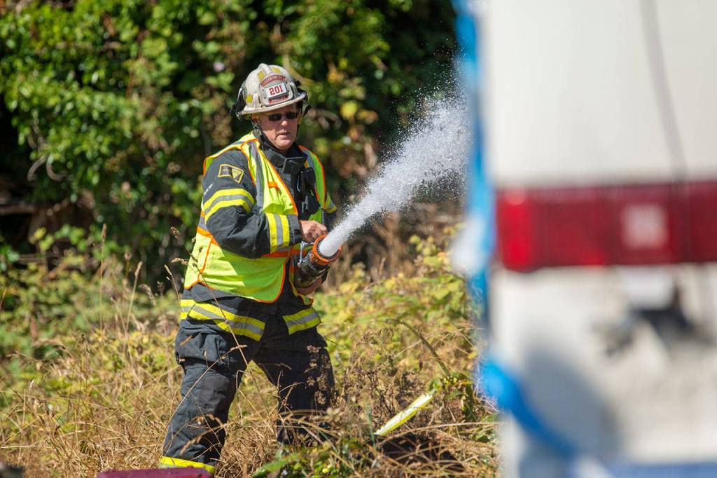 Sam Phillips, chief of Clallam County Fire District No. 2, puts water on an RV fire on the 2300 block of East Fifth Avenue in Port Angeles on Sunday. (Jesse Major/Peninsula Daily News)