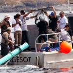 Aboard a Lummi Nation police boat, tribal members, NOAA and others use a dip net to lift a chinook salmon from a fish tote to release through the green tube as a test into waters off San Juan Island as viewed from aboard the King County Research Vessel SoundGardian on Friday. (Alan Berner/The Seattle Times via AP)