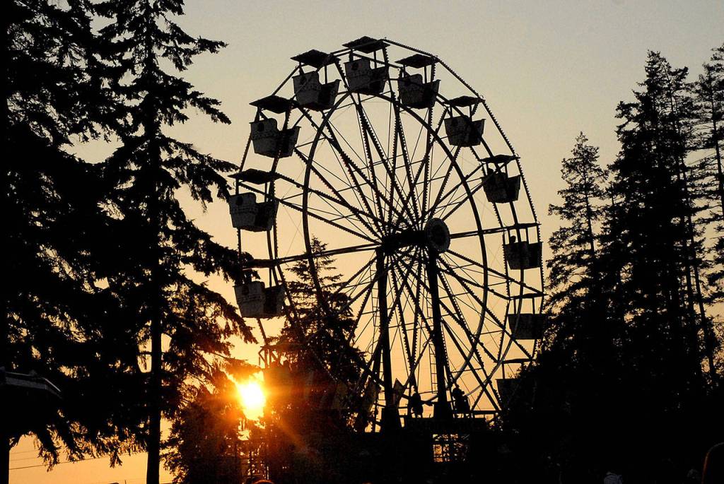 The sun sets behind the Ferris wheel at the county fair carnival on Friday evening. (Keith Thorpe/Peninsula Daily News)