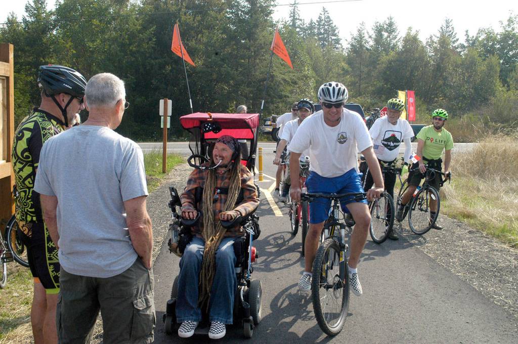 Ian Mackay and his supporters stop to celebrate after crossing the Clallam-Jefferson County line on the Olympic Discovery Trail at Diamond Point Road on Friday. Mackay had traveled on his wheelchair from Coeur dAlene, Idaho to highlight the need for wheelchair-accessible trails in Washington. (Rob Ollikainen/Peninsula Daily News)