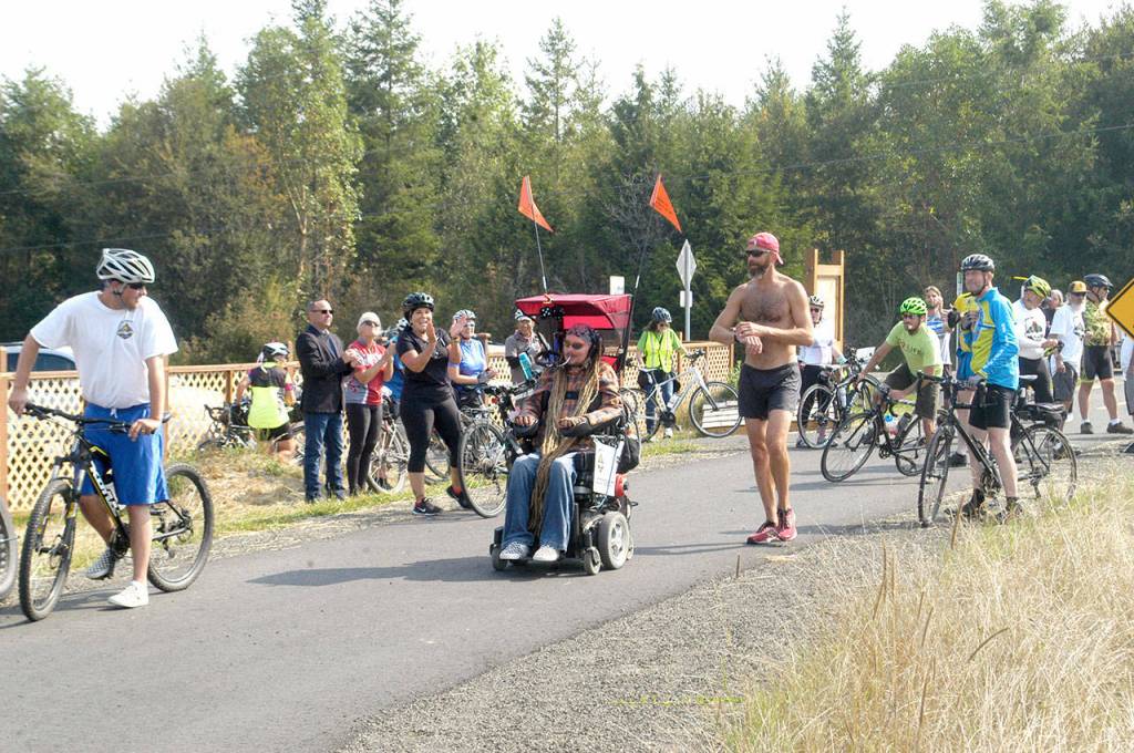Ian Mackay and his supporters stop to celebrate after crossing the Clallam-Jefferson County line on the Olympic Discovery Trail at Diamond Point Road on Friday. Mackay had traveled on his wheelchair from Coeur dAlene, Idaho to highlight the need for wheelchair-accessible trails in Washington. (Rob Ollikainen/Peninsula Daily News)