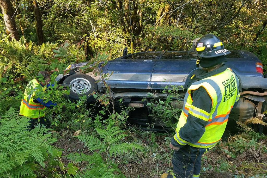 Clallam Fire District No. 2 personnel look over a vehicle that rolled down the bank of the Elwha River after the driver led police on a pursuit from Port Angeles to Olympic Hot Springs Road on Tuesday morning. (Jesse Major/Peninsula Daily News)