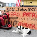 Veteran Timothy Morgan of Irondale pays his respects to the late Sen. John McCain (R-Ariz.) with a display on Sims Way in Port Townsend. (Jeannie McMacken/Peninsula Daily News)