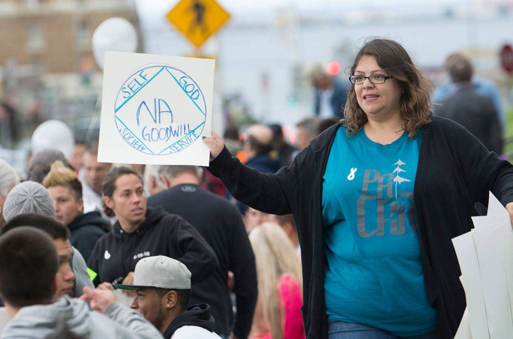 Port Angeles Citizens Action Network Board Member Rachel Ringer passes out signs at the International Overdose Awareness Day walk in Port Angeles on Friday. (Jesse Major/Peninsula Daily News)