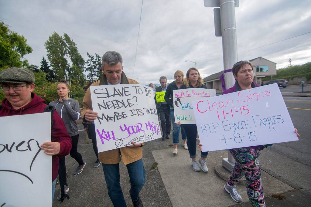 The Rev. Tom Steffen, of First United Methodist Church, holds a sign as the International Overdose Awareness Day walk makes its way toward the Port Angeles City Pier on Friday. (Jesse Major/Peninsula Daily News)