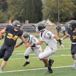 Lonnie Archibald/for Peninsula Daily News Forks Tristen Pisani, left, looks for yardage while Port Angeles Chris Guttormsen (6) and Cade Flanagan (9) defend.