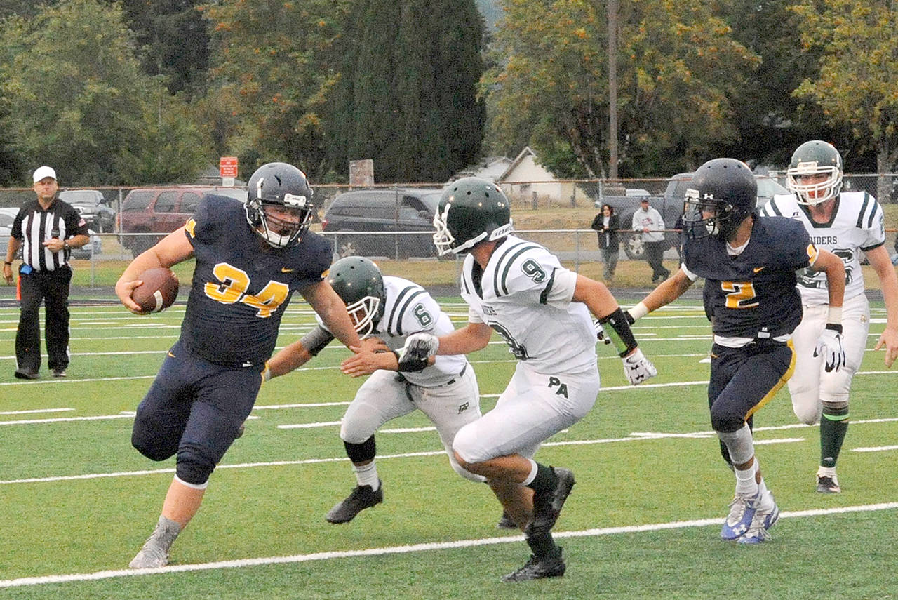 Lonnie Archibald/for Peninsula Daily News Forks Tristen Pisani, left, looks for yardage while Port Angeles Chris Guttormsen (6) and Cade Flanagan (9) defend.