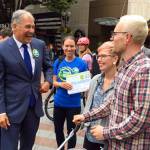 Gov. Jay Inslee speaks to people on June 28 in Seattle as he helps to gather signatures for a proposed initiative that would charge large industrial emitters a fee for their carbon emissions. (Phuong Le/The Associated Press)