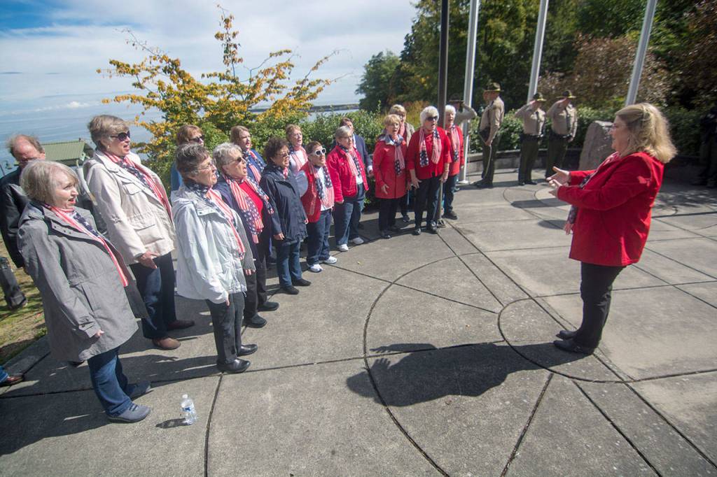 Connie Alward leads the Grand Olympics Chorus during the 9/11 ceremony in Port Angeles on Tuesday. (Jesse Major/Peninsula Daily News)