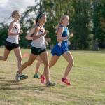 Steve Mullensky/for Peninsula Daily News Lady Redhawks Rachel Matthes, left, and Anika Avelino, center, pace themselves in the early going of the girls cross country race against North Kitsap and North Mason on Wednesday at Port Townsend Golf Course.