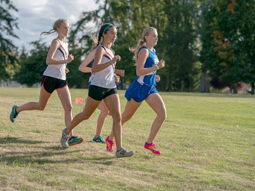Steve Mullensky/for Peninsula Daily News Lady Redhawks Rachel Matthes, left, and Anika Avelino, center, pace themselves in the early going of the girls cross country race against North Kitsap and North Mason on Wednesday at Port Townsend Golf Course.