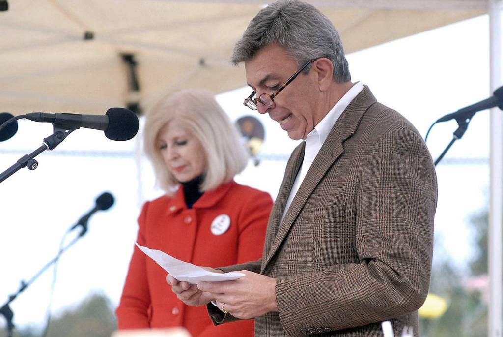 The Rev. Tom Steffen of the First United Methodist Church in Port Angeles reads a prayer during a dedication ceremony on Wednesday evening for suicide-proof fencing on the two Eighth Street bridges. Accompanying him was City Council Member Cherie Kidd. (Keith Thorpe/Peninsula Daily News)
