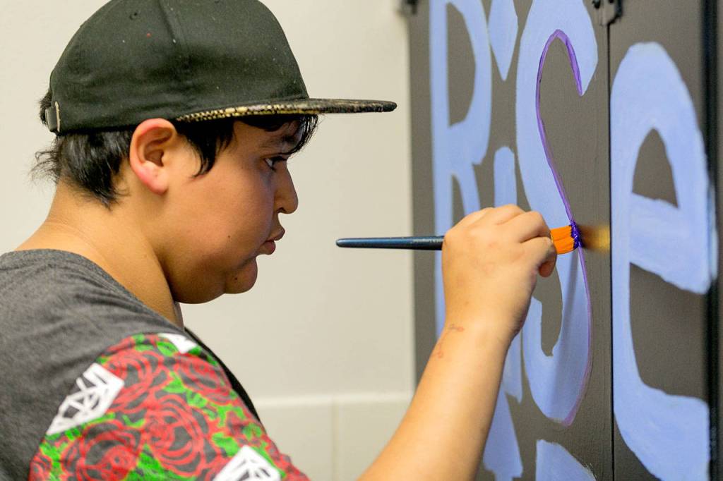Alejandro Ramos paints the stall door in the mens room at Crossroads High School in Granite Falls on Sept. 11. (Kevin Clark/The Herald)