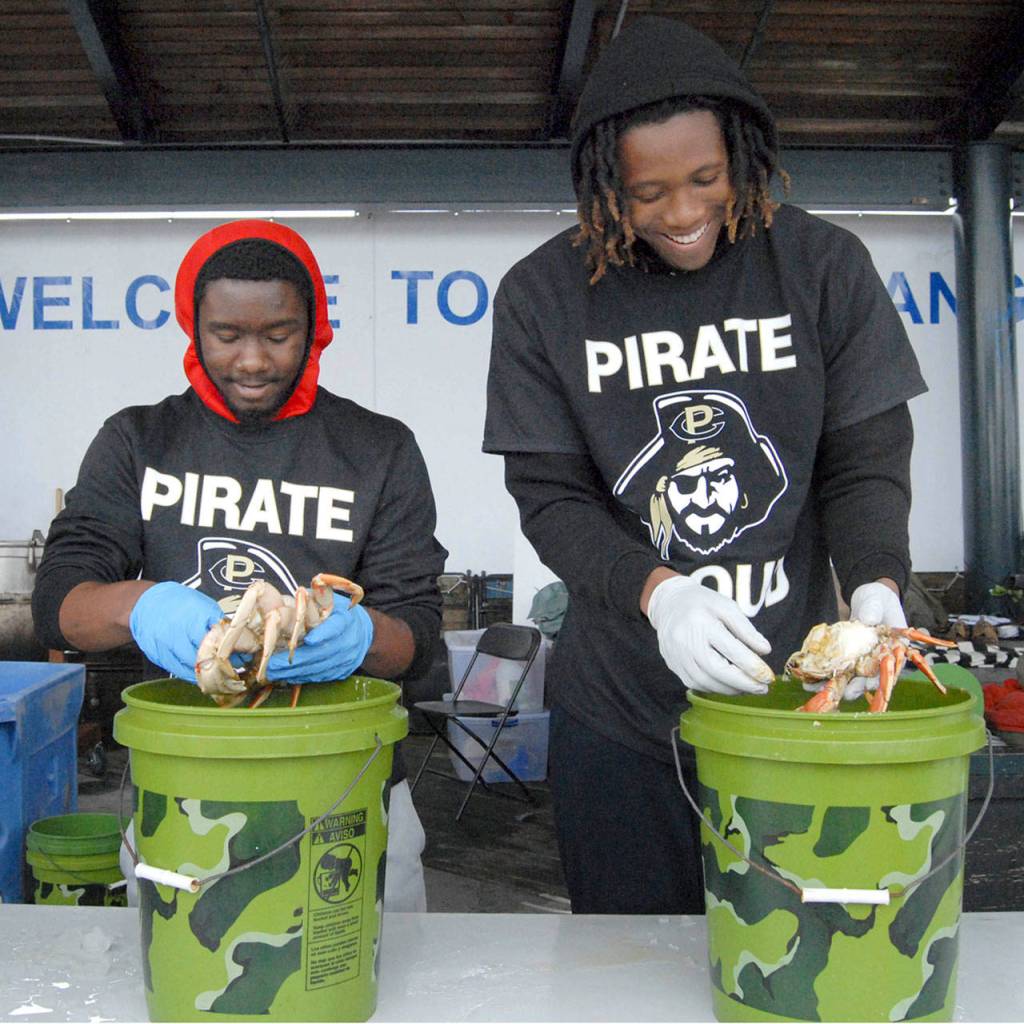 Andrew Thomas of Dallas, left, and Malik Moore of Las Vegas, both members of the Peninsula College basketball team, prepare cooked crabs for successful crab derby participants at Port Angeles City Pier. (Keith Thorpe/Peninsula Daily News)