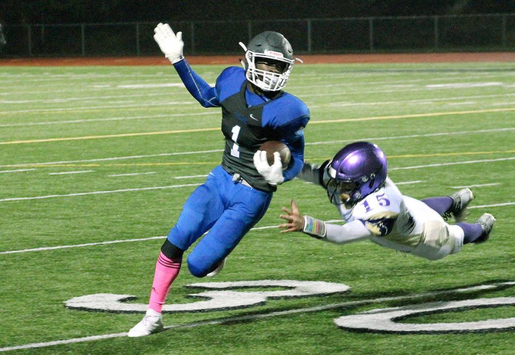Sequims Taig Wiker (15) dives while trying to tackle Olympics Malcolm Dewalt. Wiker had two interceptions in Sequims 28-9 win and 262 yards rushing on offense. (Mark Krulish/Kitsap News Group)