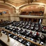 In this Feb. 7 file photo, state representatives work on the house floor at the Capitol in Olympia. (Ted S. Warren/The Associated Press)