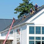 Power Trip Energys solar installation team assembles the InvisaMount railings on the roof of the Nora Porter Commons Building at Fort Worden in September. The low profile of the rails combined with the black frames of the modules creates a clean aesthetic on the roofs. (Megan Claflin)