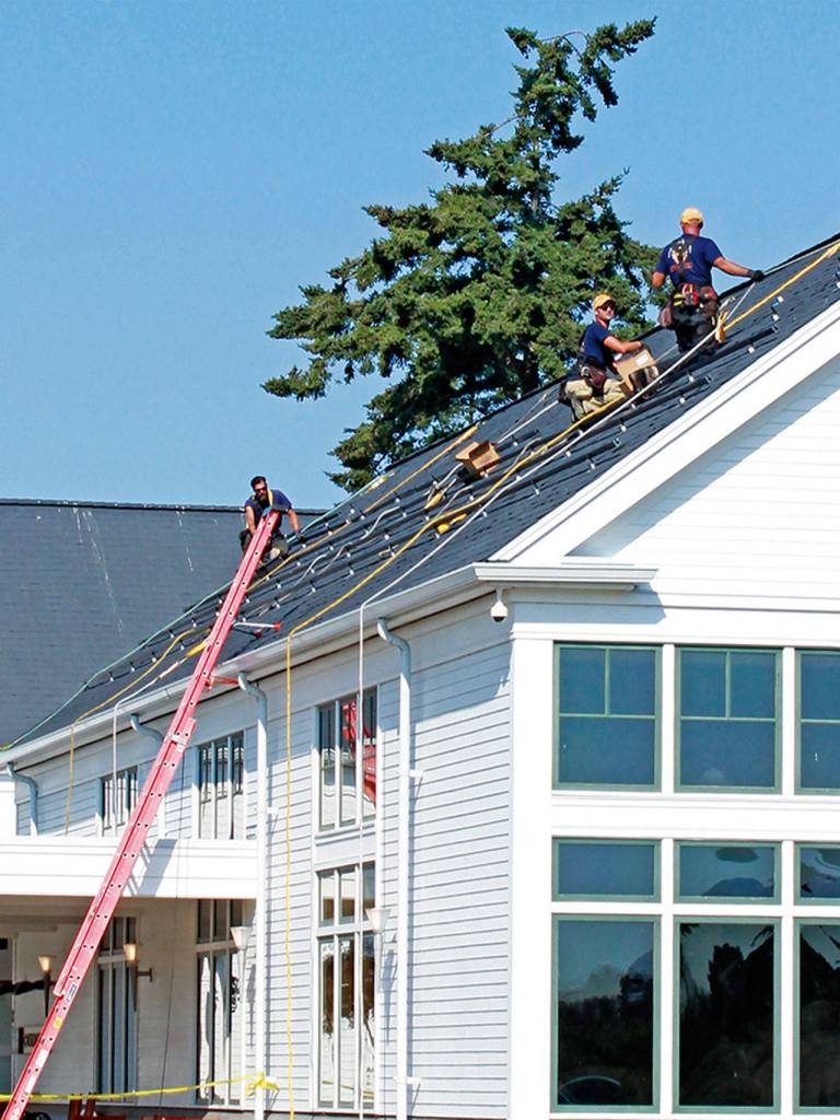 Power Trip Energys solar installation team assembles the InvisaMount railings on the roof of the Nora Porter Commons Building at Fort Worden in September. The low profile of the rails combined with the black frames of the modules creates a clean aesthetic on the roofs. (Megan Claflin)