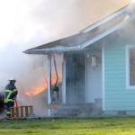 A firefighter sprays water onto a blaze that destroyed a garage and did heavy damage to an adjoining house at 2418 W. Edgewood Drive near Port Angeles on Tuesday. (Keith Thorpe/Peninsula Daily News)