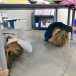 Kaida Rodrigues, left, and Kaleb Kruse tucked under their desks Thursday at Salish Coast Elementary School for the Great Washington ShakeOut. (Jeannie McMacken/Peninsula Daily News)