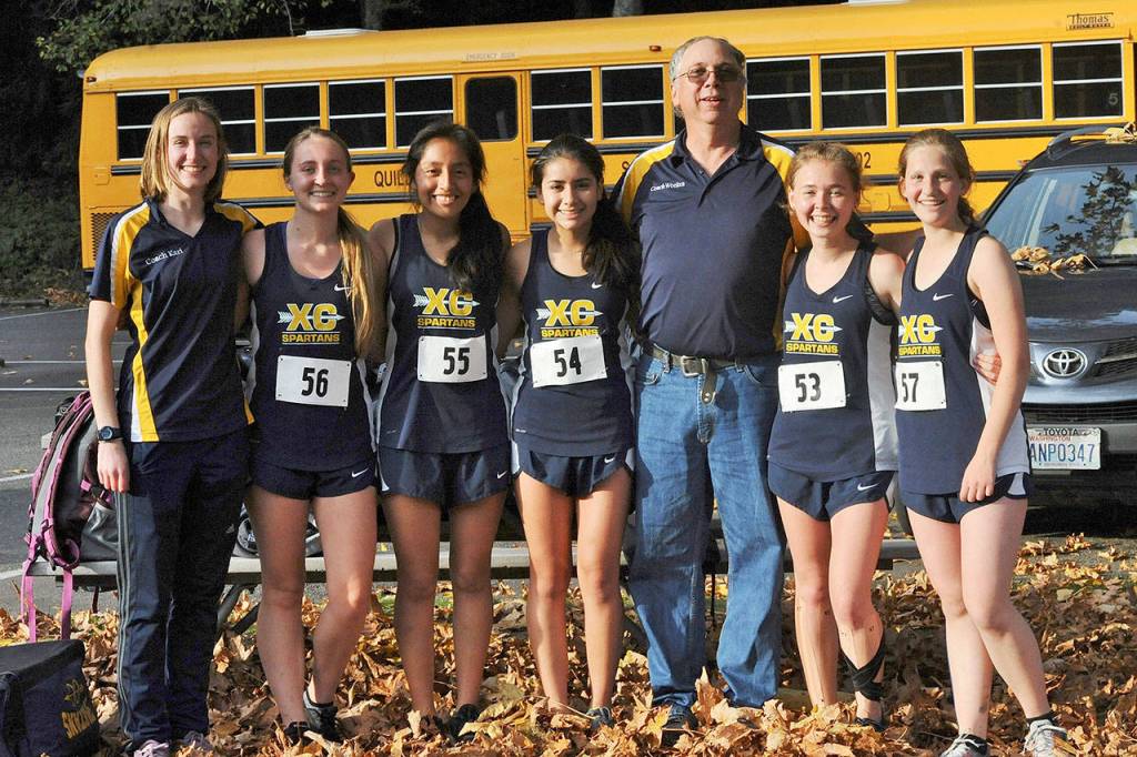 The Forks girls cross country team took first place Thursday at Montesano during the 1 A Evergreen league meet. From left, are assistant coach Kari Larson, Kayleen Bailey, Melissa Galindo, Karen Ensastegui Salazar, head coach Brian Weekes, Madelyn Archibald and Savannah Meyer. (Lonnie Archibald/for Peninsula Daily News)
