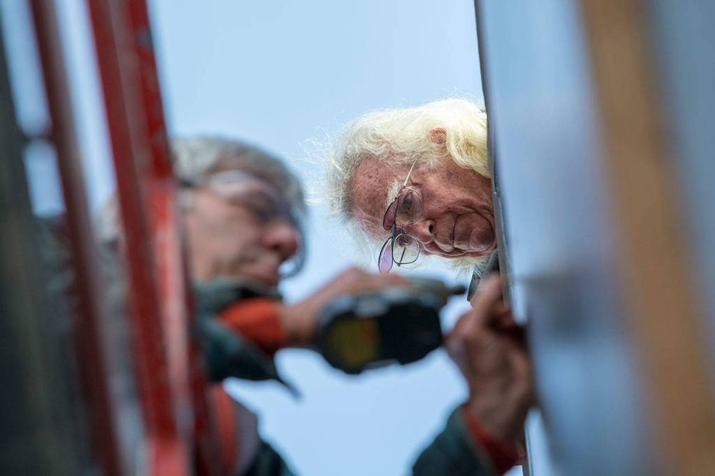 Bob Stokes watches on as crews mount a panel of the Pacific Fleet mural on the west side of the former Station 51 Taphouse in Port Angeles on Monday afternoon. (Jesse Major/Peninsula Daily News)