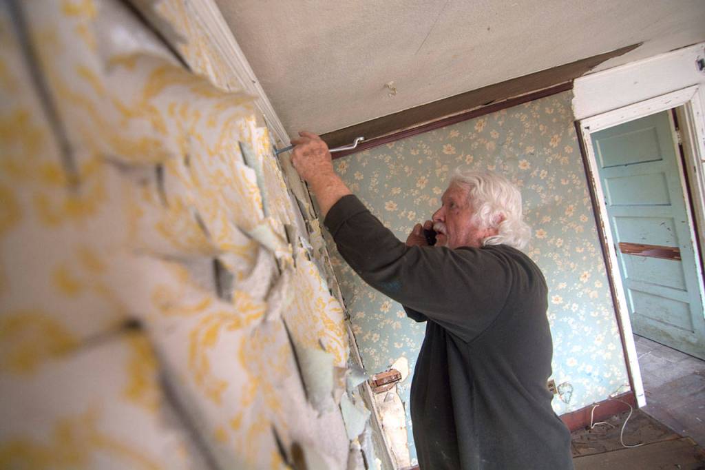 Jackson Smart works on anchoring the Pacific Fleet mural to the west side of the former Station 51 bar in Port Angeles on Monday. (Jesse Major/Peninsula Daily News)