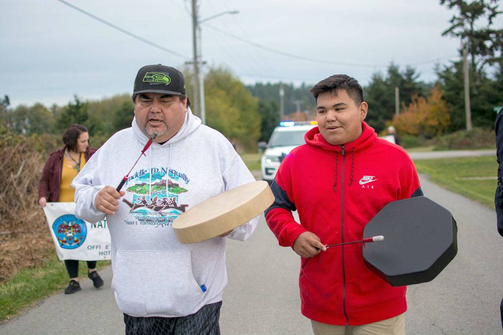 Lower Elwha Kallam Tribal member Mark Charles, left, and his nephew Dylan Thomas of the Esquimalt tribe, sing and drum during the domestic violence awareness walk at the Lower Elwha Klallam Tribes reservation Wednesday afternoon. (Jesse Major/Peninsula Daily News)