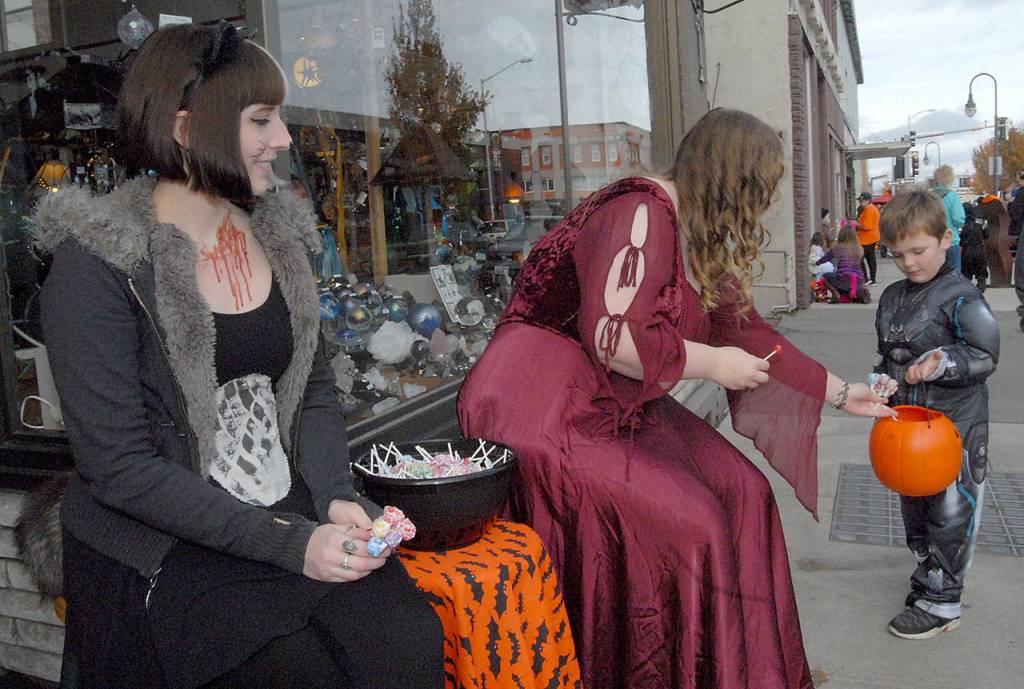 Five-year-old Anthony Cousins receives treats from Taylor Thomas, left, and Sarah Ogerly of Olympic Stained Glass in Port Angeles on Halloween. (Keith Thorpe/Peninsula Daily News)