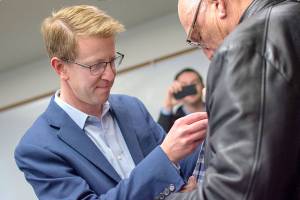 U.S. Rep. Derek Kilmer puts a pin on a veterans jacket during a pinning ceremony for Vietnam War era veterans in Port Ludlow Thursday evening. (Jesse Major/Peninsula Daily News)