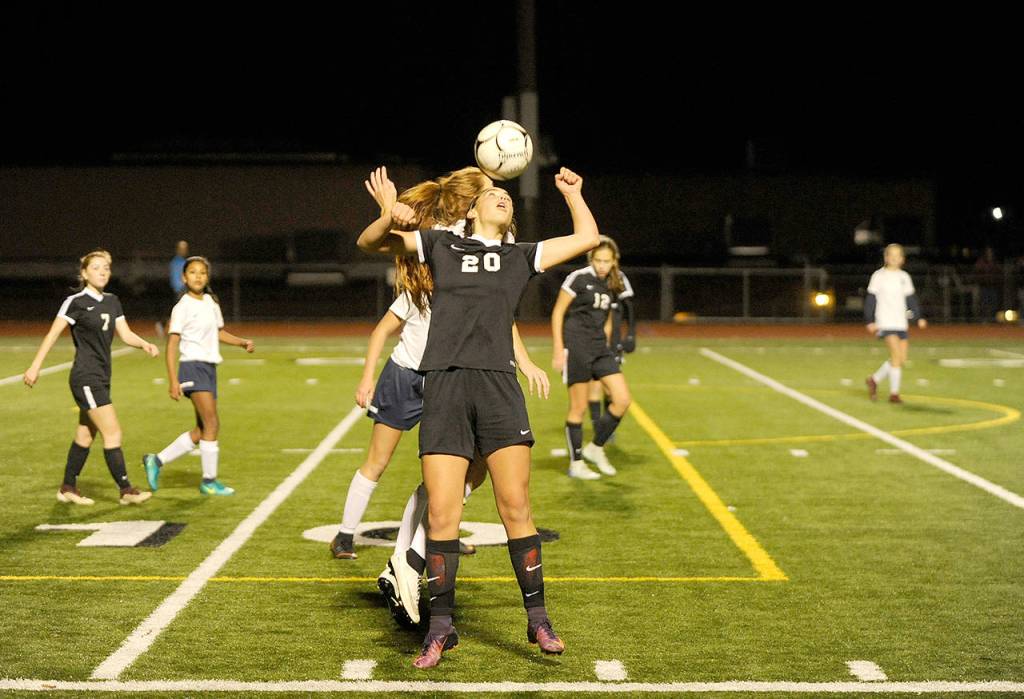 Sequims Hope Glasser (20) heads the ball over an Ellensburg defender in the first half. Sequim Gazette photo by Michael Dashiell