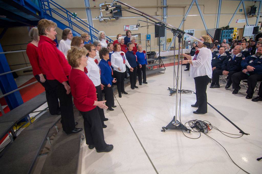 Connie Alward directs the Grand Olympics Chorus during the Veterans Day ceremony at U.S. Coast Guard Air Station/Sector Field Office Port Angeles on Sunday. (Jesse Major/Peninsula Daily News)