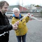 Volunteers Alex Walter and Peggy Norris help to create a rope of Christmas lights on Saturday that will be used to decorate the area around a seasonal ice skating rink and winter village being constructed in a city parking lot in the 100 block of West Front Street in downtown Port Angeles. (Keith Thorpe/Peninsula Daily News)