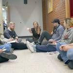Director Kelly Doran, center, discusses a scene with students during an impromptu read-through in the hall as the set is constructed.