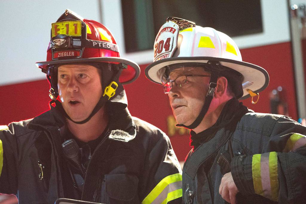 Port Angeles Fire Department Capt. Kelly Ziegler, left, talks with Clallam Fire District No. 2 Assistant Fire Chief Mike DeRousie as firefighters fight a blaze at Sunrise Meats in Port Angeles late Saturday night. (Jesse Major/Peninsula Daily News)