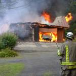 Assistant Fire Chief Tony Hudson reports in about the fire as he awaits a water tender to arrive to fight a Blyn fire from atop a steep hill. (Matthew Nash/Olympic Peninsula News Group)