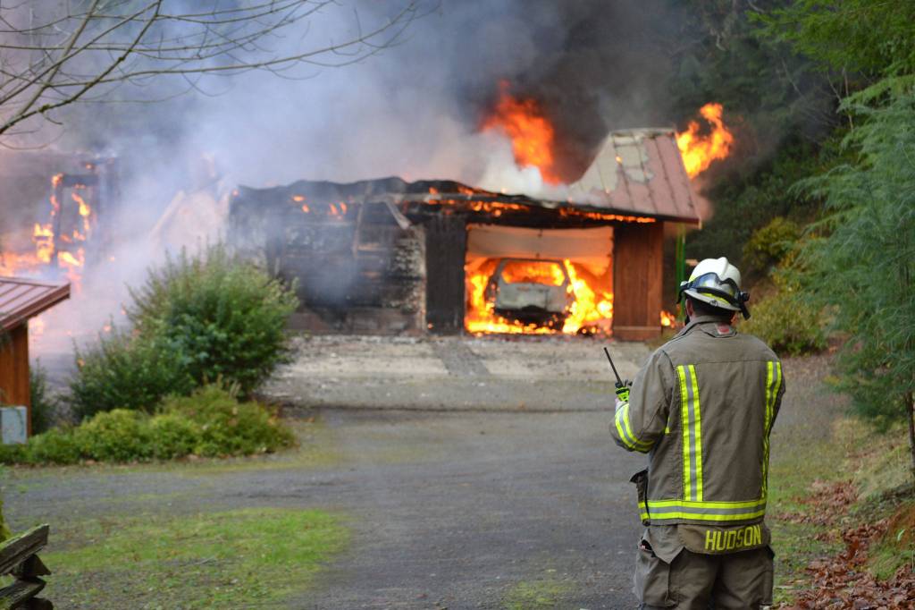 Assistant Fire Chief Tony Hudson reports in about the fire as he awaits a water tender to arrive to fight a Blyn fire from atop a steep hill. (Matthew Nash/Olympic Peninsula News Group)