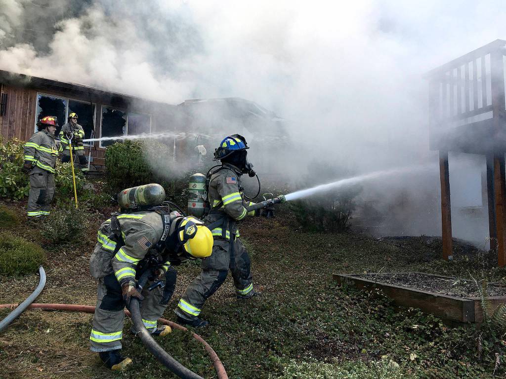 Clallam County firefighters attempt to combat flames on a Blyn house fire Monday. (Matthew Nash/Olympic Peninsula News Group)