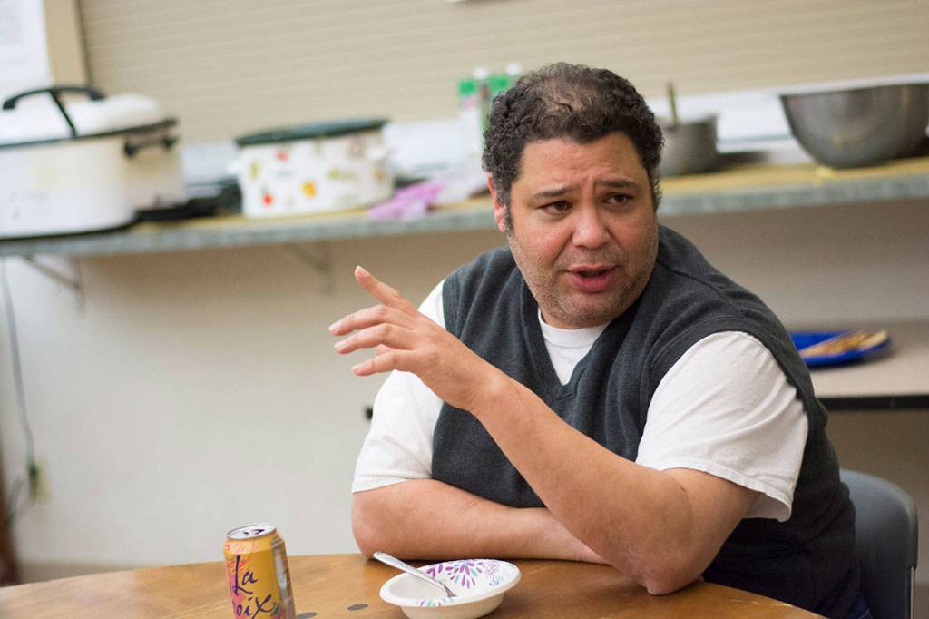 Manny Aybar, director of shelter services for Serneity House of Clallam County, talks with people at the night-by-night shelter Wednesday evening. (Jesse Major/Peninsula Daily News)