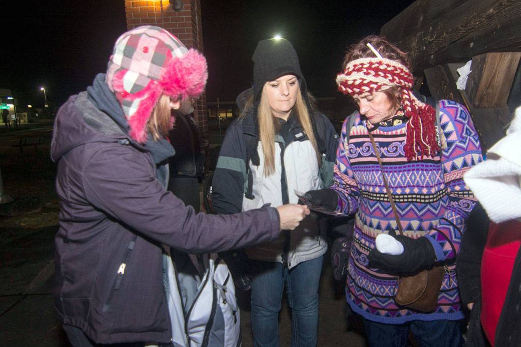 Amy Miller, left, gives hand warmers to Susan, who asked that her last name not be published. Susan said she has been homeless since she was 12 years old. (Jesse Major/Peninsula Daily News)