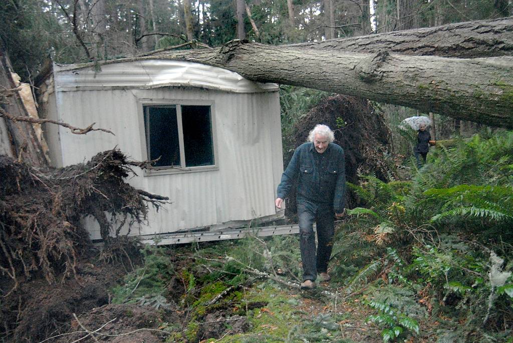 Dave Becker emerges from the wreckage of his mobile home after it and an adjoining structure were crushed by falling trees in the Old Mill Road area south of Port Angeles on Friday. (Keith Thorpe/Peninsula Daily News)