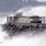 Waves crash against a seawall at high tide as cars maneuver past during a windstorm Thursday in Seattle. (Elaine Thompson/The Associated Press)