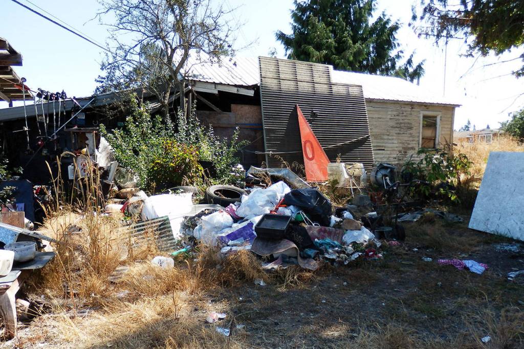 Garbage is piled against a home at 2337 E. Pioneer Road on Aug. 8, 2017. The property was recently cleaned after Clallam Countys code enforcement program got involved and the property was sold to a new owner. (Clallam County)