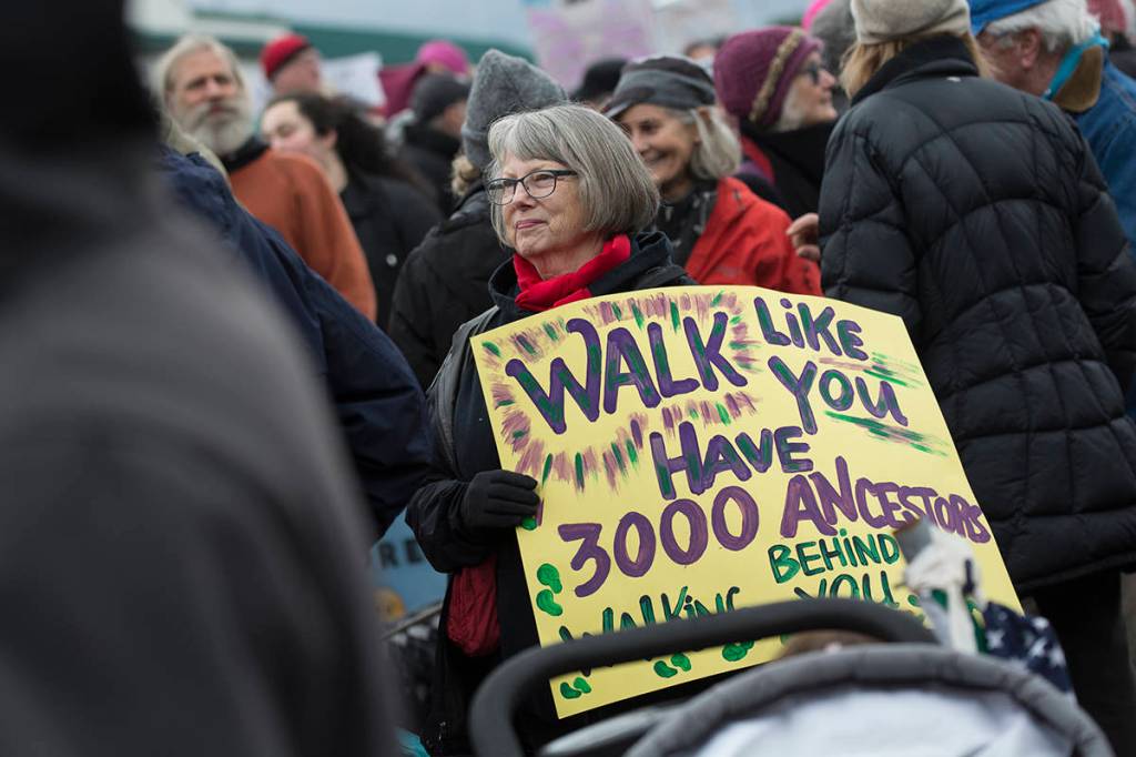 Jo Blair of Port Townsend carries a sign at the third annual Olympic Peninsula Womxns Wave in Port Townsend on Sunday. (Jesse Major/Peninsula Daily News)